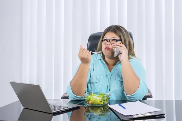 Fat Asian woman eating lettuce salad while calling — 스톡 사진
