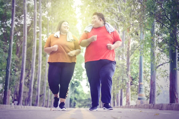 Tlustý pár jogging šťastně v parku za slunečného dne — Stock fotografie
