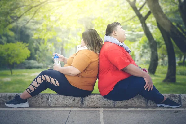 Tlustý pár se opírá jeden o druhého v parku — Stock fotografie