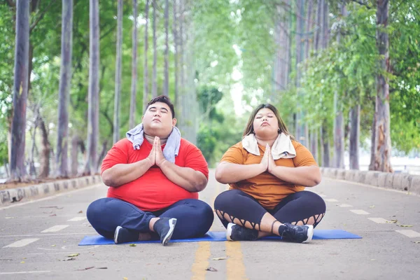 Fat couple meditating while relaxing on the road — Stock Photo, Image