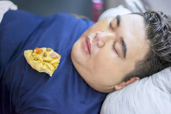 Толстяк спит, пока пицца лежит на его теле. — стоковое фото