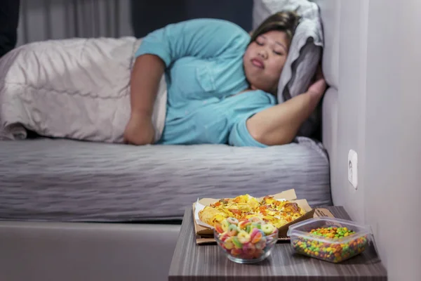 Товста жінка спить, поки її нездорові продукти лежать — стокове фото