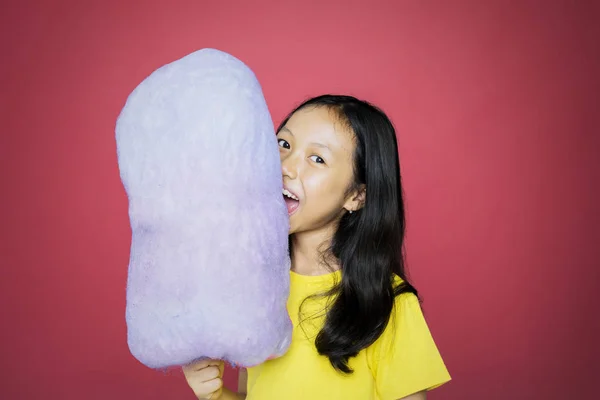 Girl biting a cotton candy while looking at camera — Stock Photo, Image