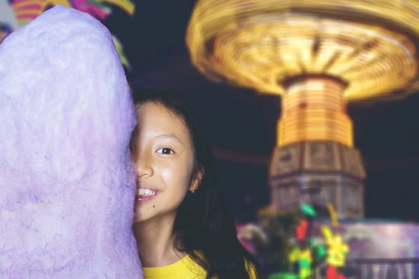 Дівчина прикриває обличчя за бавовняними цукерками в парку — стокове фото