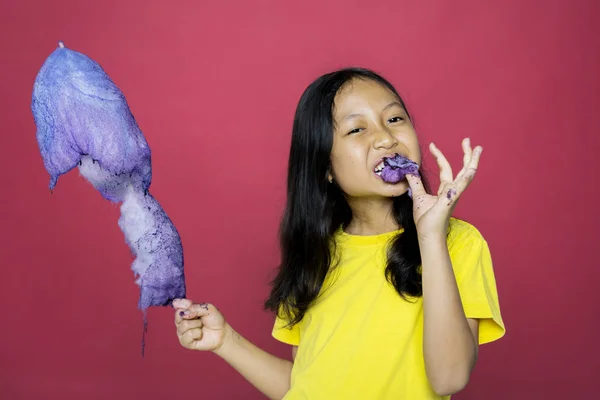 Dívka drží bonbón při kousání roztržené části — Stock fotografie