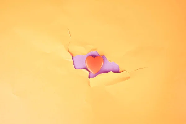 Pequeño caramelo de amor en la grieta de la pared naranja — Foto de Stock
