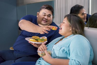 Şişman Asyalı çift romantik bir şekilde donut yiyor.