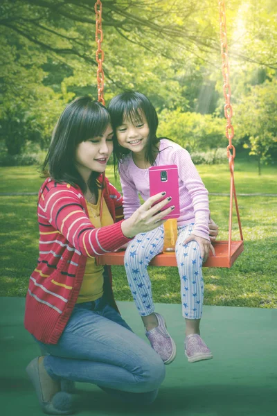 Femme prenant un selfie avec sa fille sur une balançoire — Photo