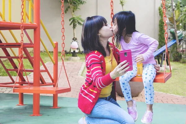 Woman taking a selfie withe her kid while kissing — Stock Photo, Image