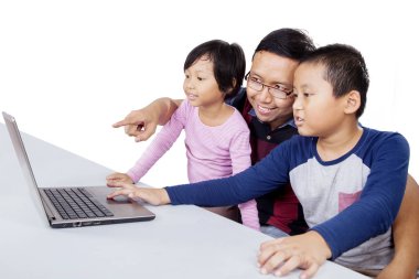 Çocuklarına dizüstü bilgisayar kullanmayı öğreten bir adam.