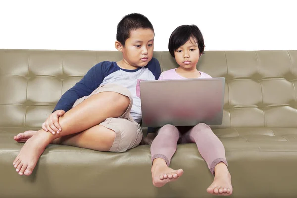 Adorables niños asiáticos que operan un ordenador portátil en serio —  Fotos de Stock