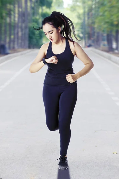 Krásná žena kontroluje své hodinky při joggingu — Stock fotografie