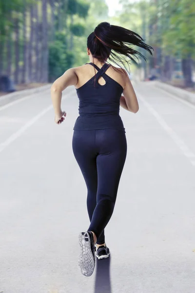 Unidentified young woman jogging on the park road — Stock Photo, Image