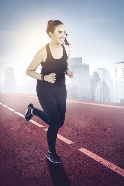 Frau joggt fröhlich auf rotem Asphalt — Stockfoto