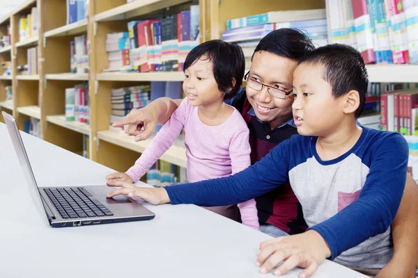 Twee kinderen studeren met hun vader met laptop — Stockfoto