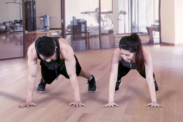 Jong paar doen push up in fitness centrum — Stockfoto