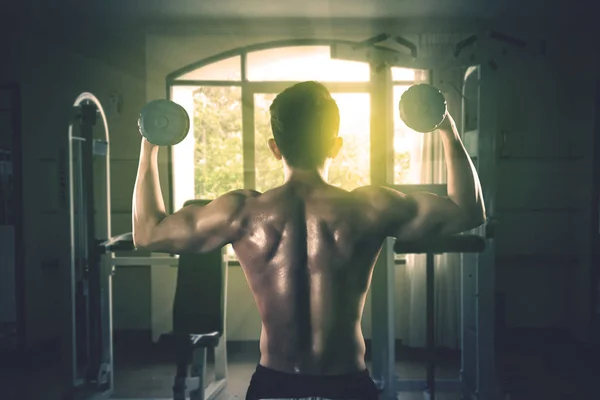 Young man holding dumbbells at gym — Stock Photo, Image