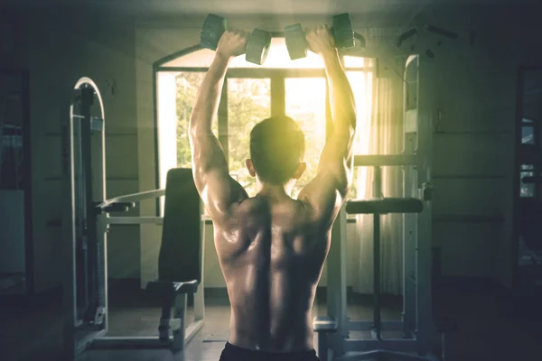 Young man lifting dumbbell at gym — 스톡 사진