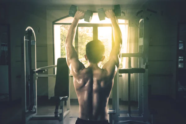 Joven levantando pesas en el gimnasio —  Fotos de Stock