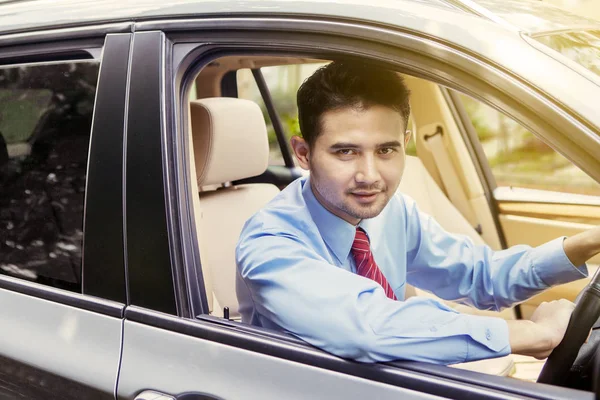 Επιχειρηματίας οδηγεί ένα αυτοκίνητο, ενώ χαμογελά στην κάμερα — Φωτογραφία Αρχείου
