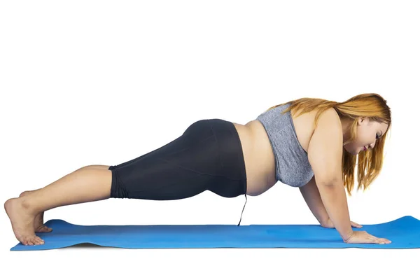 Obese woman doing push up on the mat — Stock Photo, Image