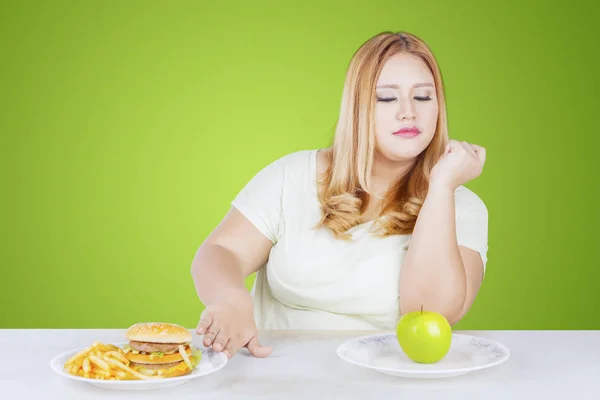 Mujer obesa rehusando comida chatarra en la mesa —  Fotos de Stock