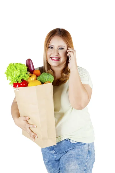 Överviktig kvinna som bär papperspåse med grönsaker — Stockfoto