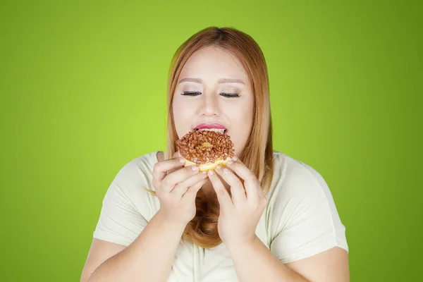 Mulher com excesso de peso comendo donuts no estúdio — Fotografia de Stock