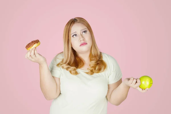 Şişman kadın donut ve elma meyvesi tutuyor. — Stok fotoğraf