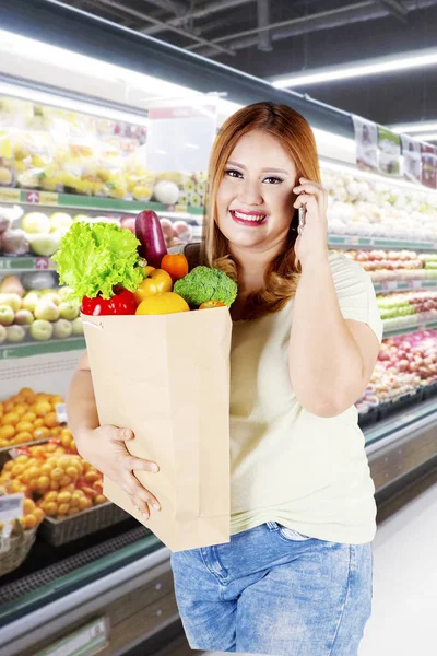 太りすぎの女性は野菜と紙袋を保持している — ストック写真