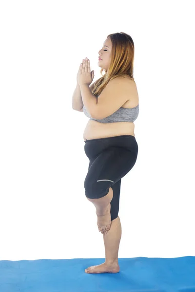Overweight woman practicing yoga with one leg — Stock Photo, Image