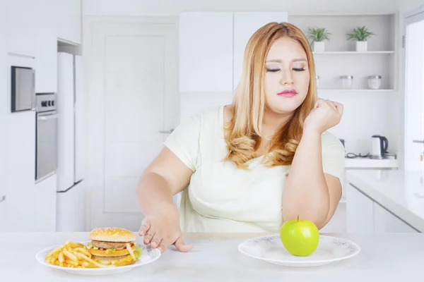 Overweight woman rejecting fast foods in kitchen — 스톡 사진