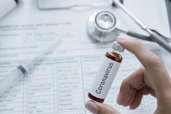 Hand met een medicijnflesje met het etiket Coronavirus — Stockfoto