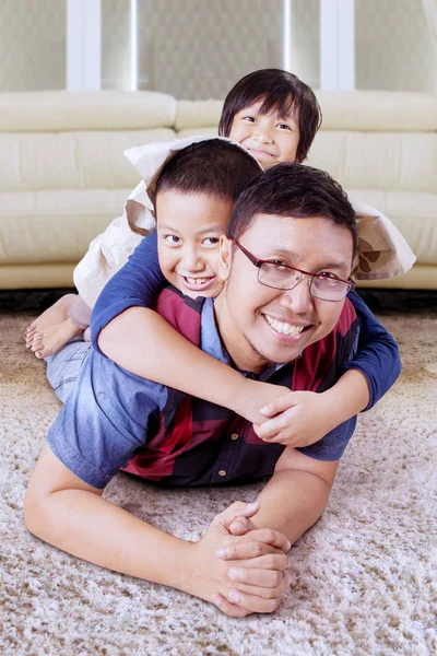 Kids cuddling on their fathers back in their home — 스톡 사진