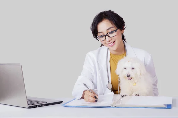 Veterinaria escribiendo algunos documentos junto con su mascota — Foto de Stock