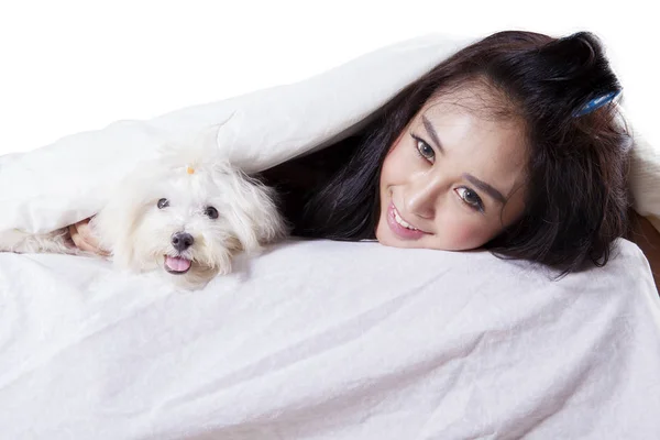 Woman smiling and lying in the bed with her dog — Stock Photo, Image