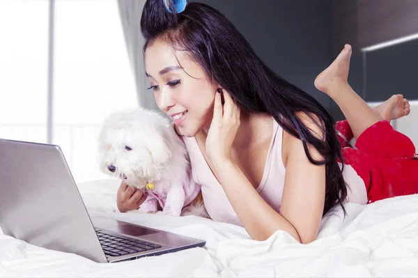 Mujer trabajando con su perro blanco en su dormitorio — Foto de Stock