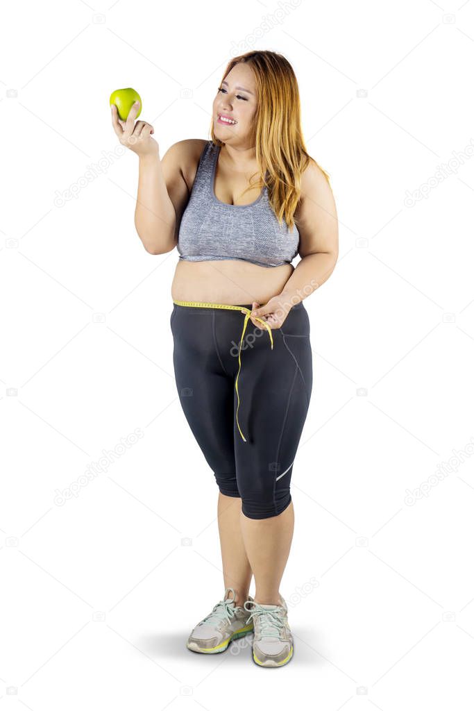 Obese woman with apple fruit and measuring tape