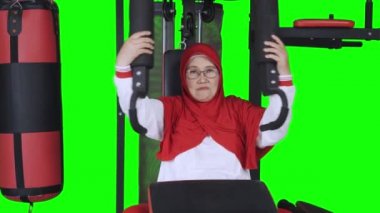 Olgun Müslüman kadın spor makinesiyle egzersiz yapıyor, video.
