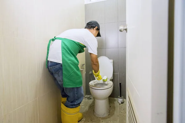 Professionele schoonmaakster die een vuile spoeltoiletbril opruimt — Stockfoto