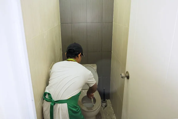 Прибиральник прибирає брудне змивне сидіння туалету — стокове фото