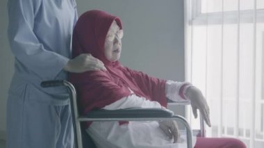 Yaşlı Müslüman kadın, tekerlekli sandalyede otururken felç geçirdikten sonra hemşiresi tarafından ağırlandı. 4k çözünürlükte çekiliyor