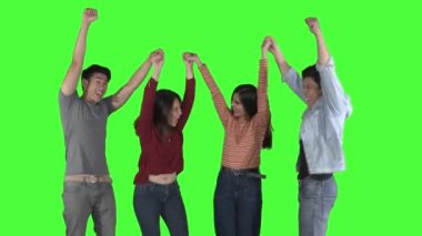 Bir grup mutlu genç insan, stüdyoda dans ederken el ele tutuşup el ele tutuşuyorlar. Yeşil ekran arkaplanlı 4k çözünürlükte çekilen