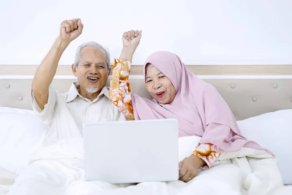 Couple âgé acclamant tout en utilisant leur ordinateur portable — Photo