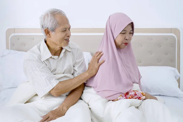 Elderly man patting his angry muslim wife shoulder — 图库照片