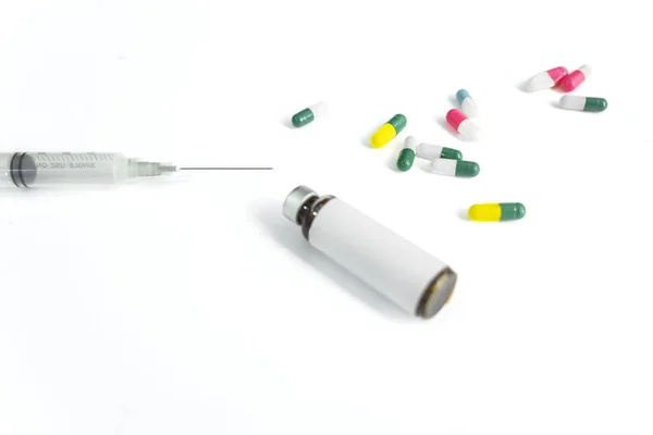 Медицинская бутылка со шприцем и капсулами в белом — стоковое фото