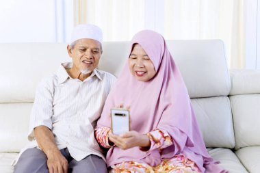 Portrait of elderly muslim couple video calling