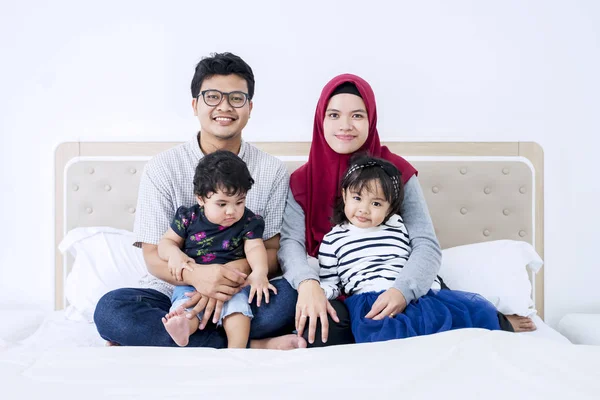 Muslim parents holding their children on a bed — Stock Photo, Image