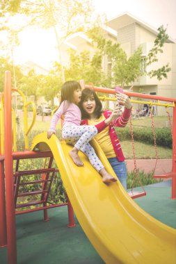 Kız ve anne parkta selfie çekiyorlar.