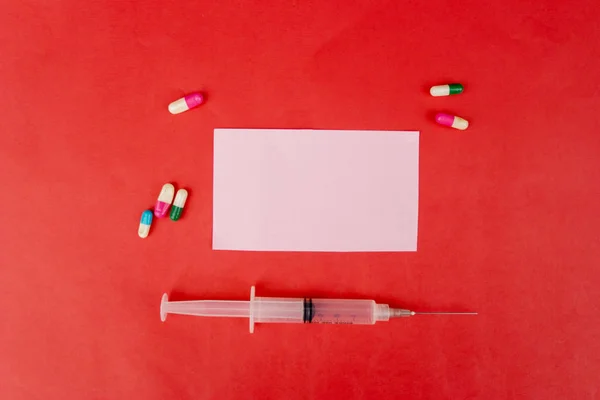 Injekční stříkačka a tablety kolem průhledného štítku — Stock fotografie